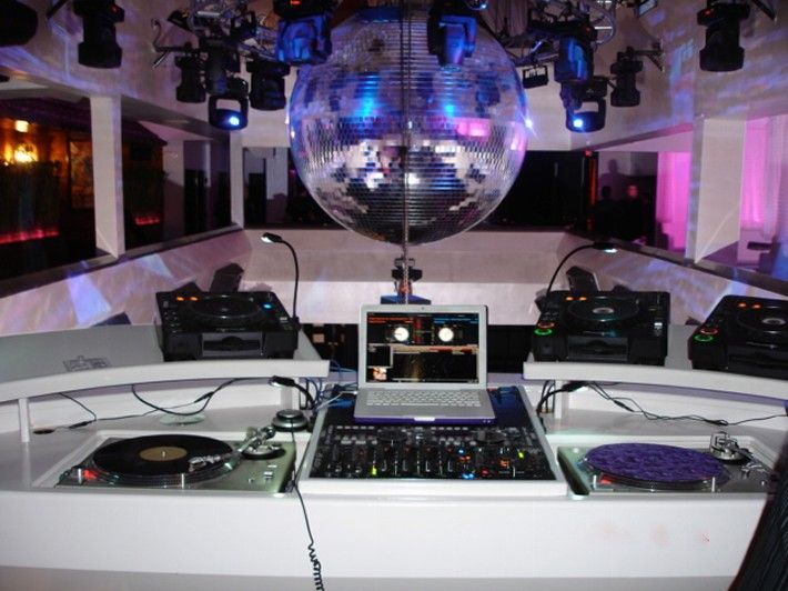 A dj booth with a laptop and a disco ball in the background
