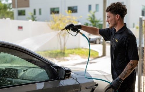 Mason washing a car with a hose