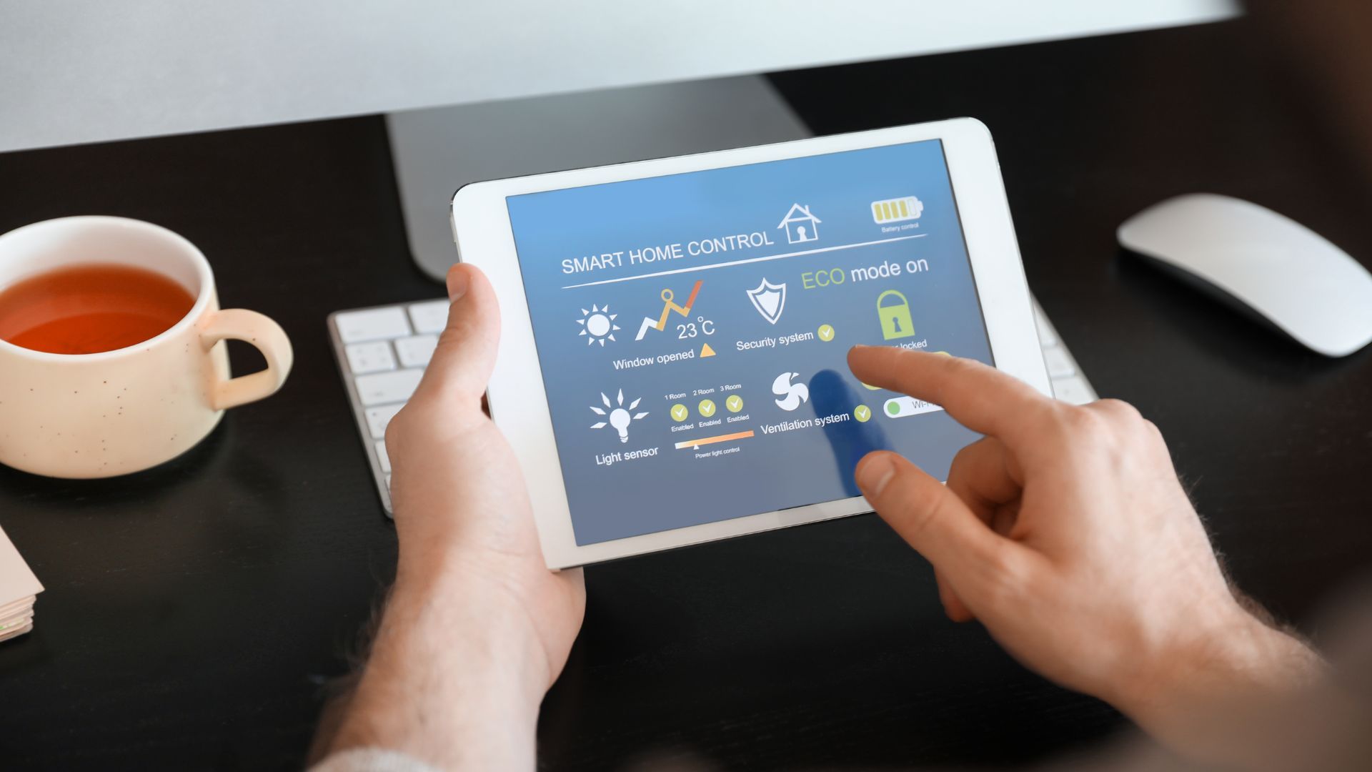 A person is using a tablet computer while sitting at a desk with a cup of tea.