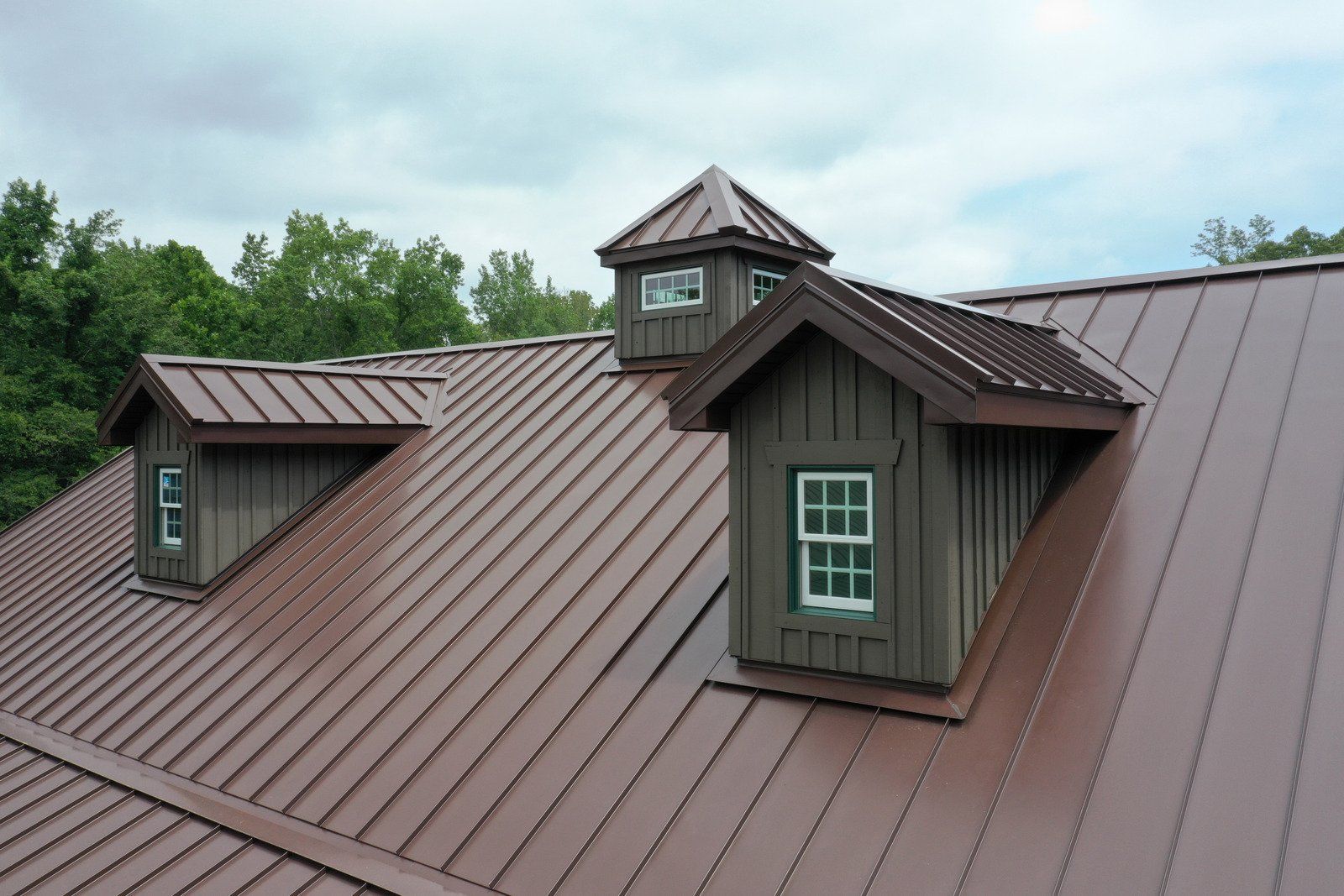 Brown metal roof with three dormers and a cupola.