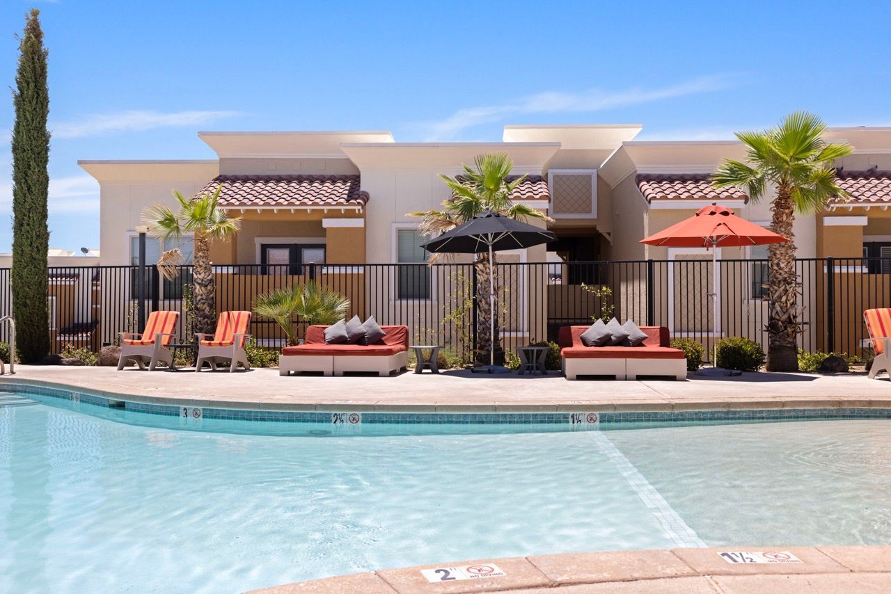 Outdoor pool area at an apartment community with lounge chairs and umbrellas.