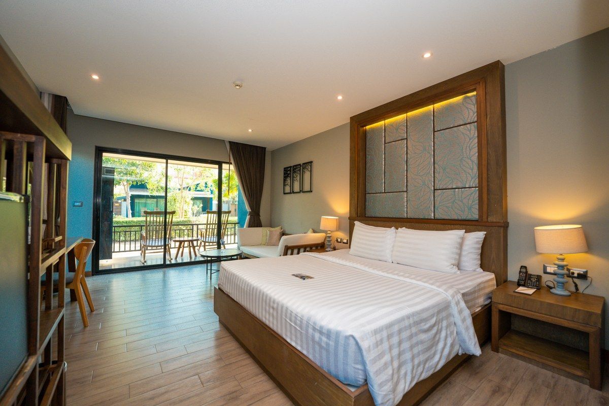 Hotel room with a bed, desk, and sliding door to a patio.