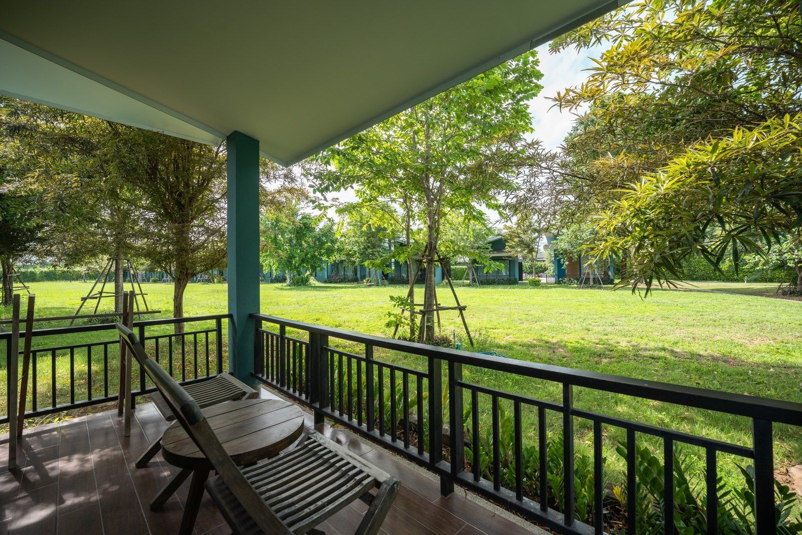Balcony with chairs overlooking a green lawn and trees.