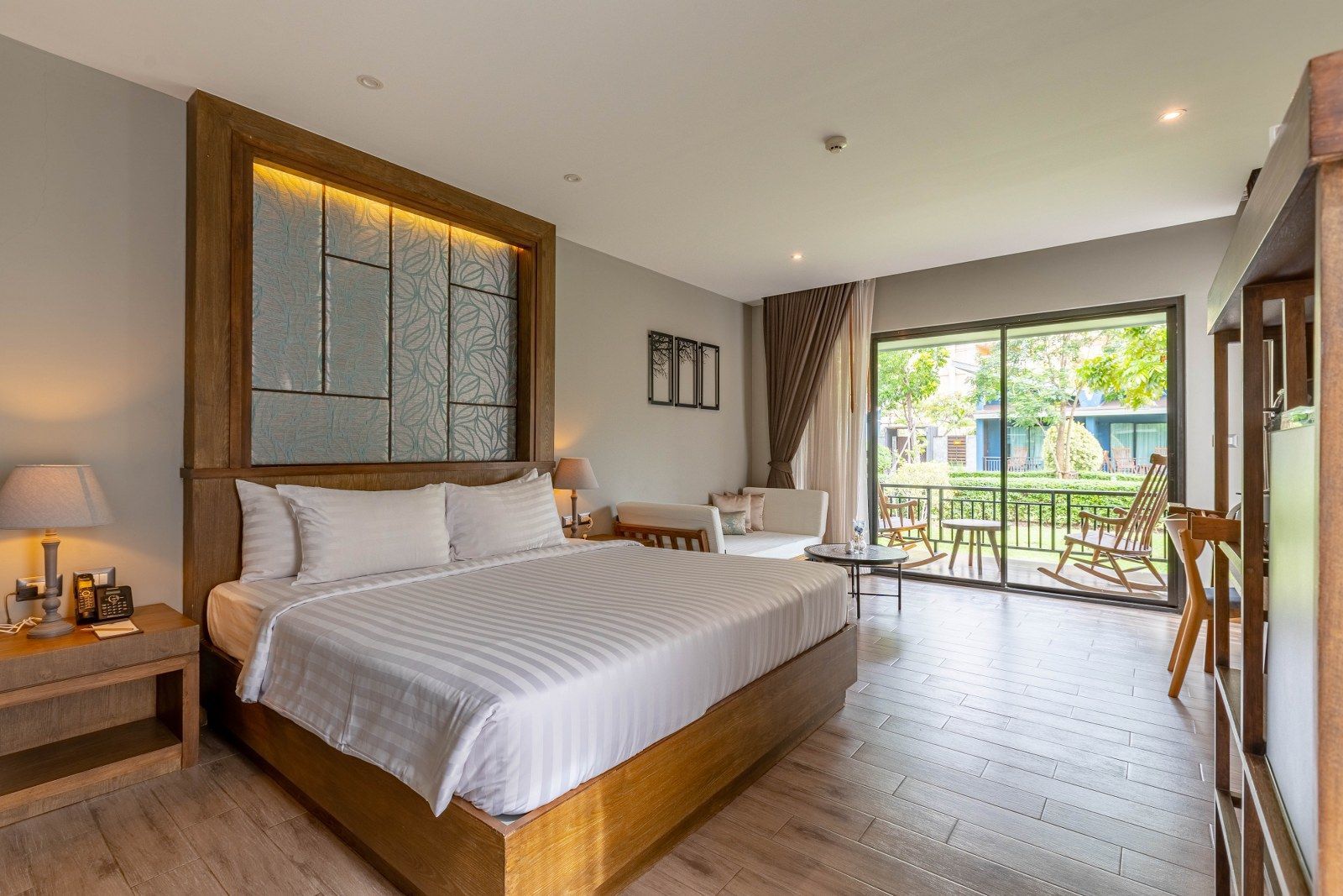 Hotel room with king bed, balcony, and outdoor view.