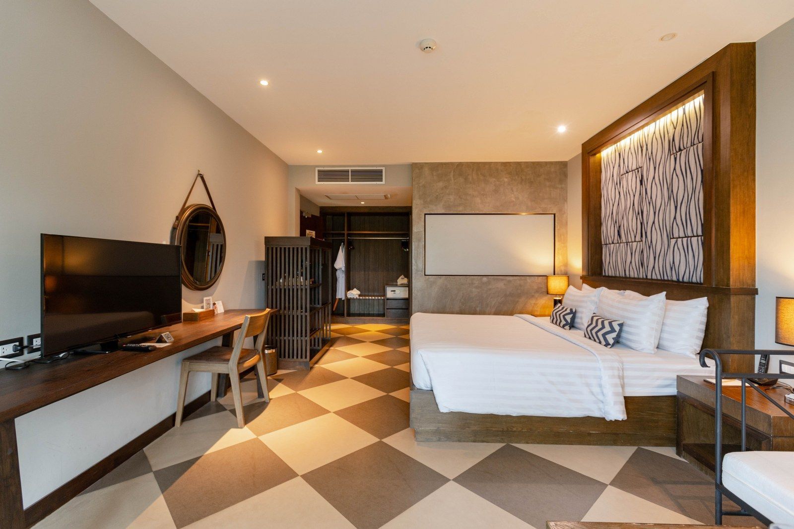 Bedroom with large bed, TV, desk, closet, and checkerboard floor.