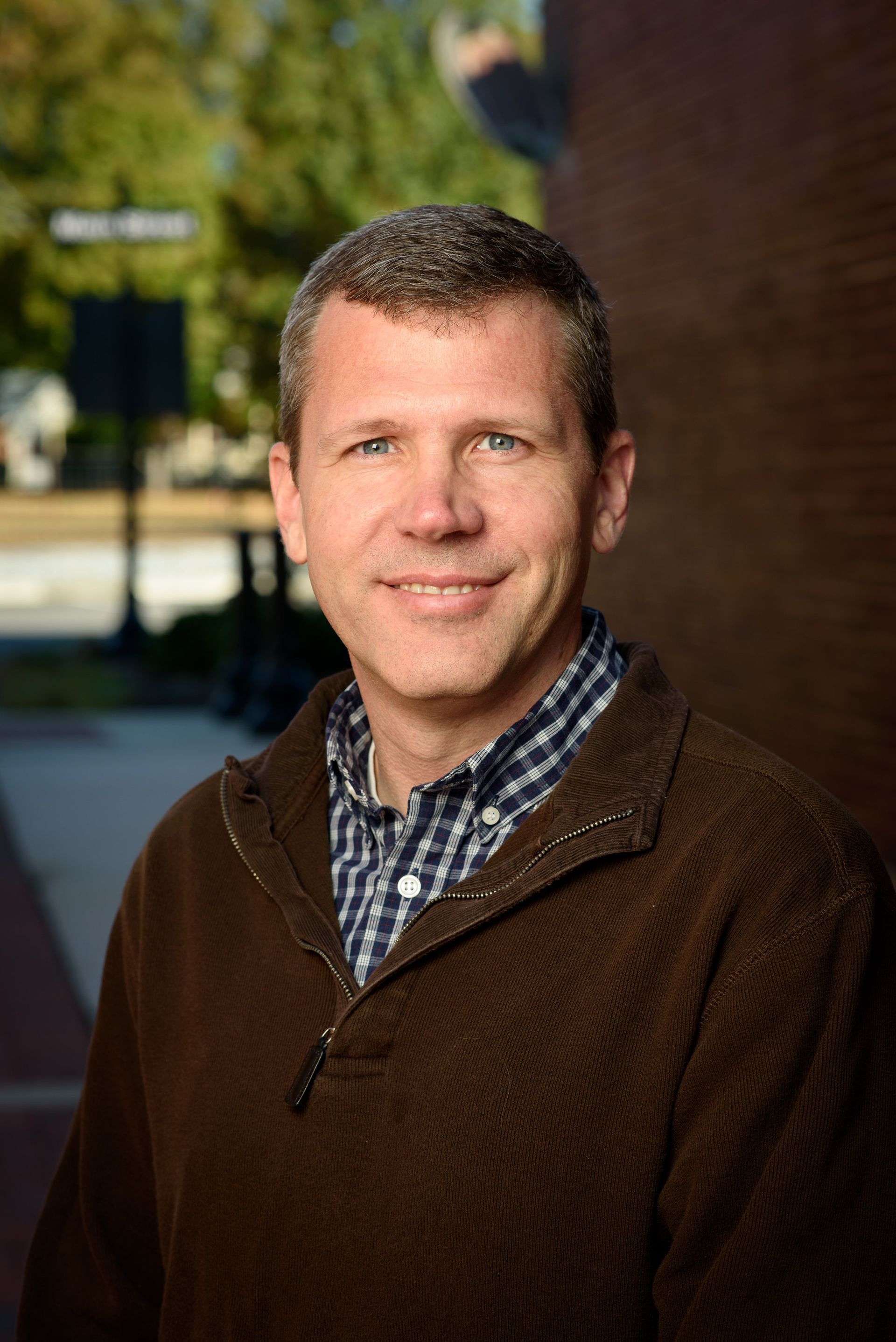 A woman is sitting at a desk with a laptop and a vase of flowers.