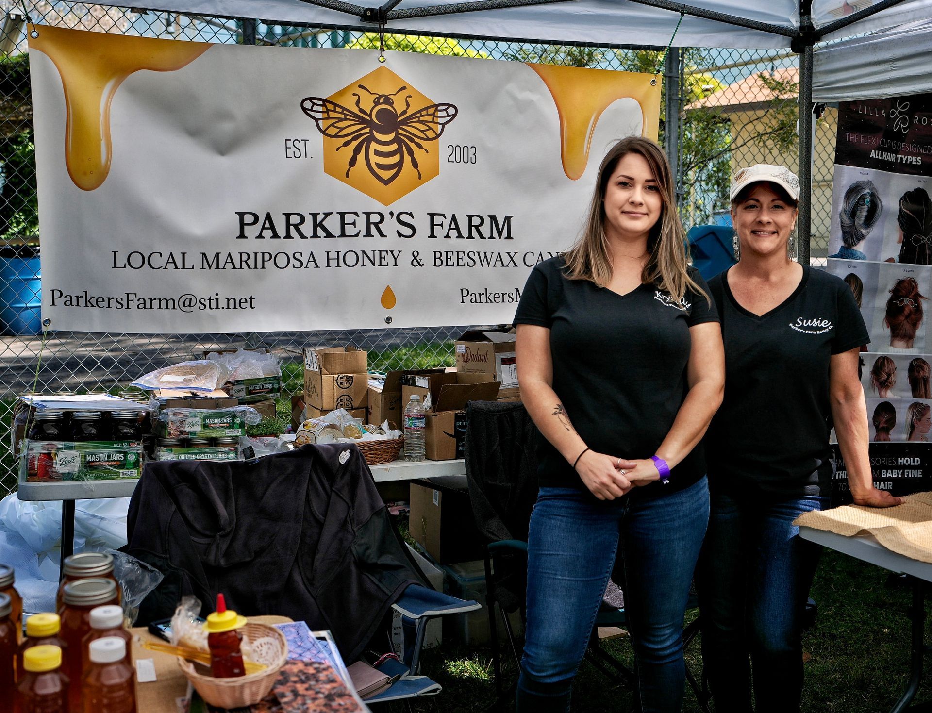 a photo of two women standing in a honey booth selling honey.