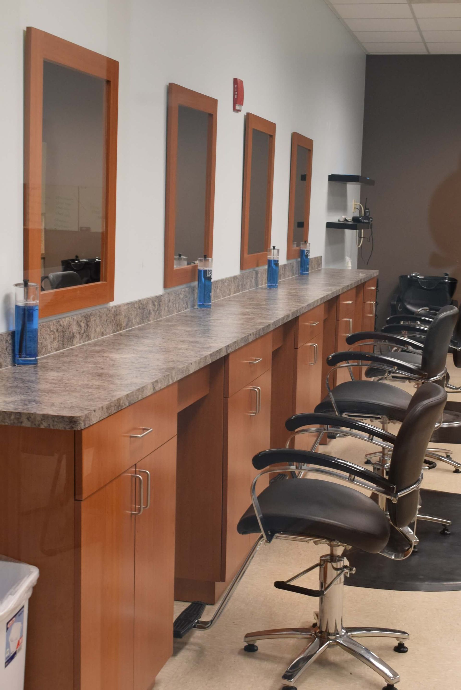 A row of hair salon chairs and mirrors in a room