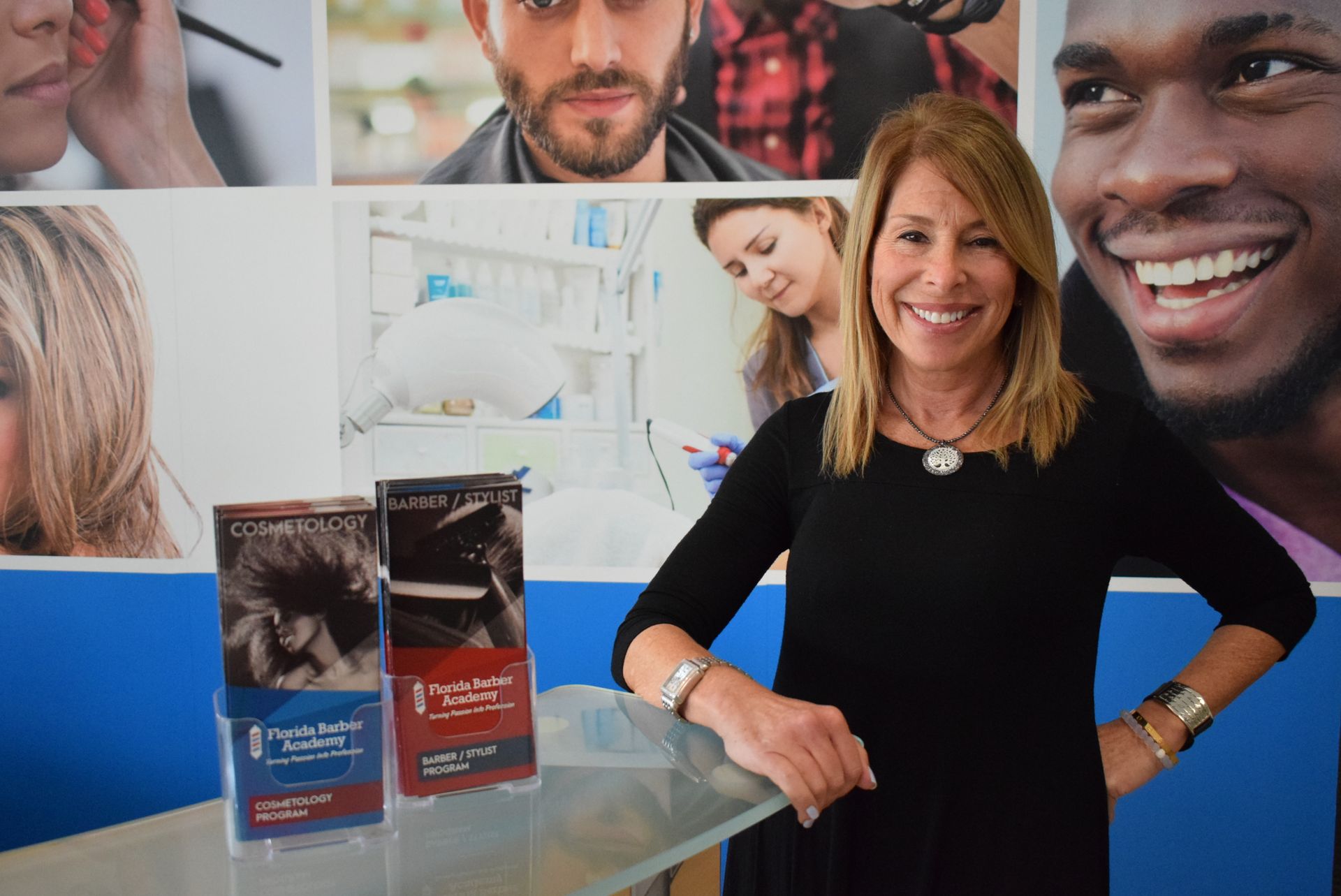 A woman is standing in front of a wall with pictures of people.