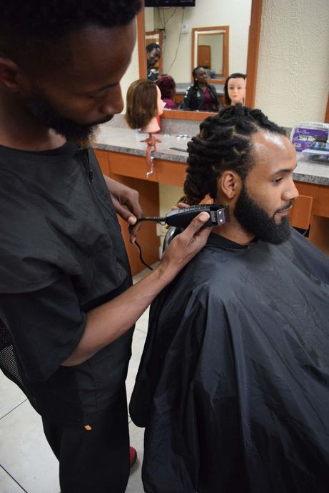 A man is getting his hair cut by a barber in a salon.