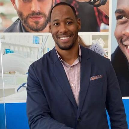 A man in a suit is smiling in front of a picture of himself