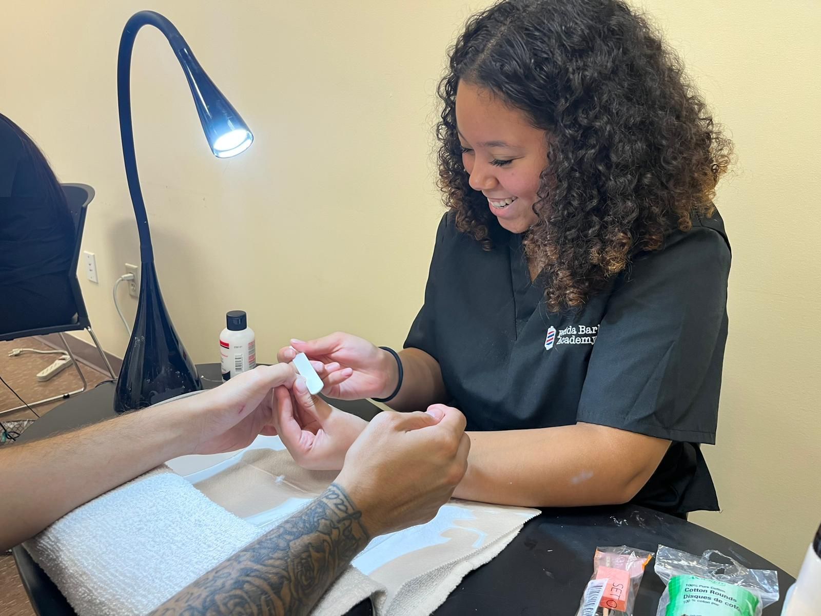 A woman is giving a man a manicure at a nail salon.