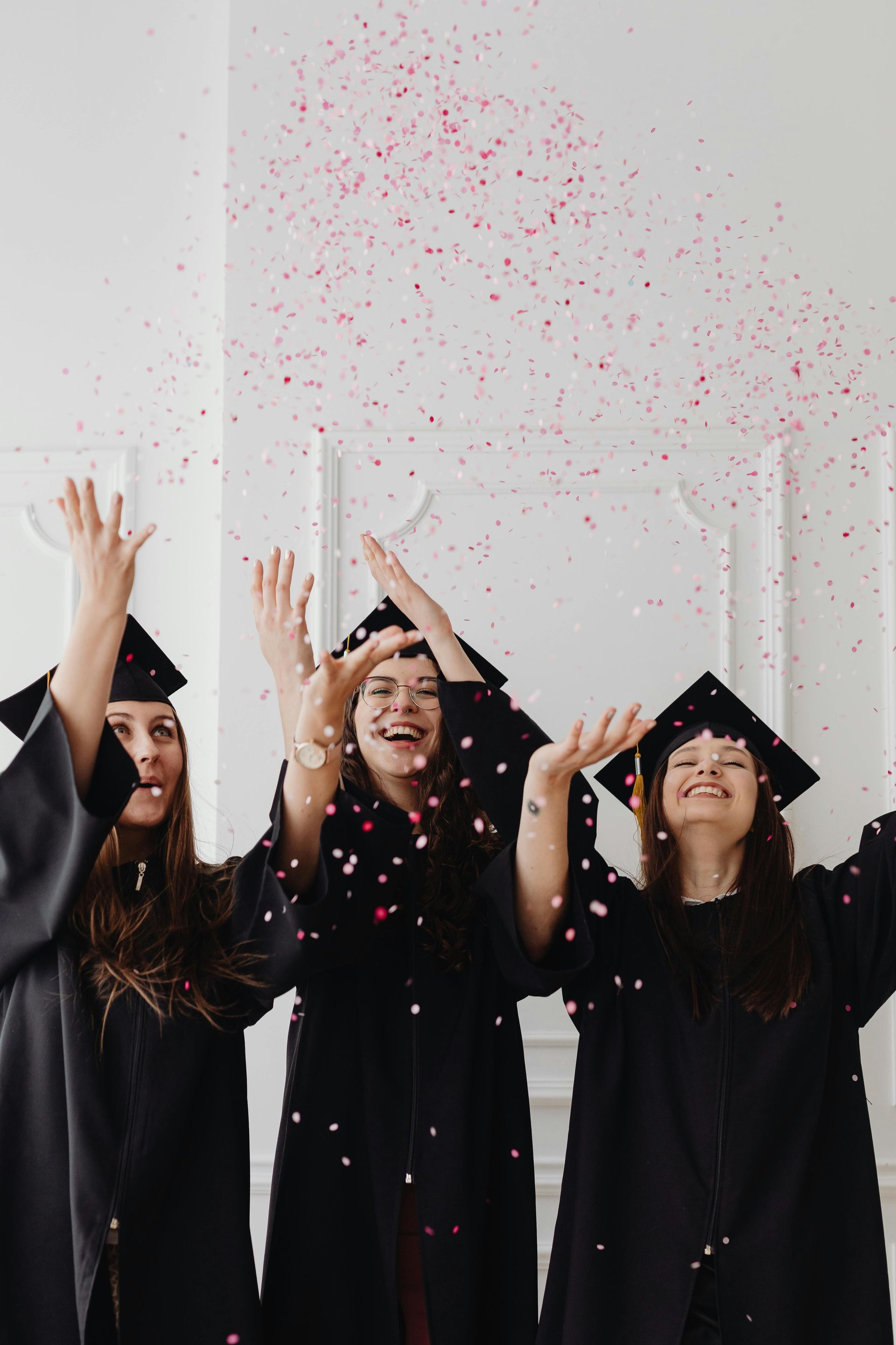 A group of graduates are throwing confetti in the air.