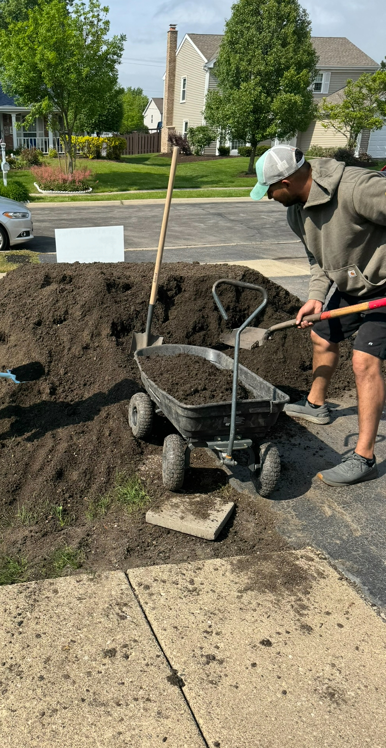 A man is shoveling dirt into a wheelbarrow.
