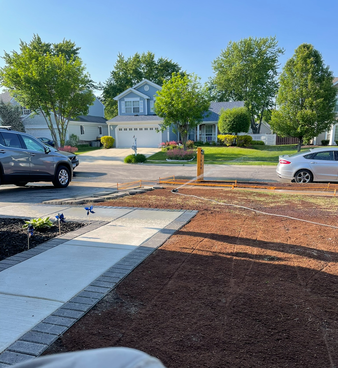 A car is parked on the side of the road in front of a house.