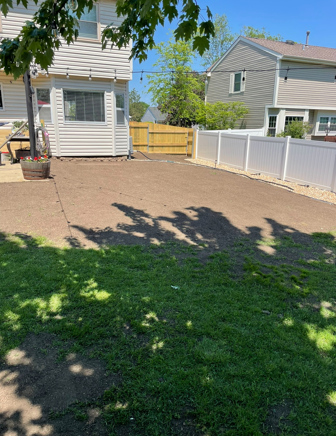 A backyard with a white fence and a house in the background.