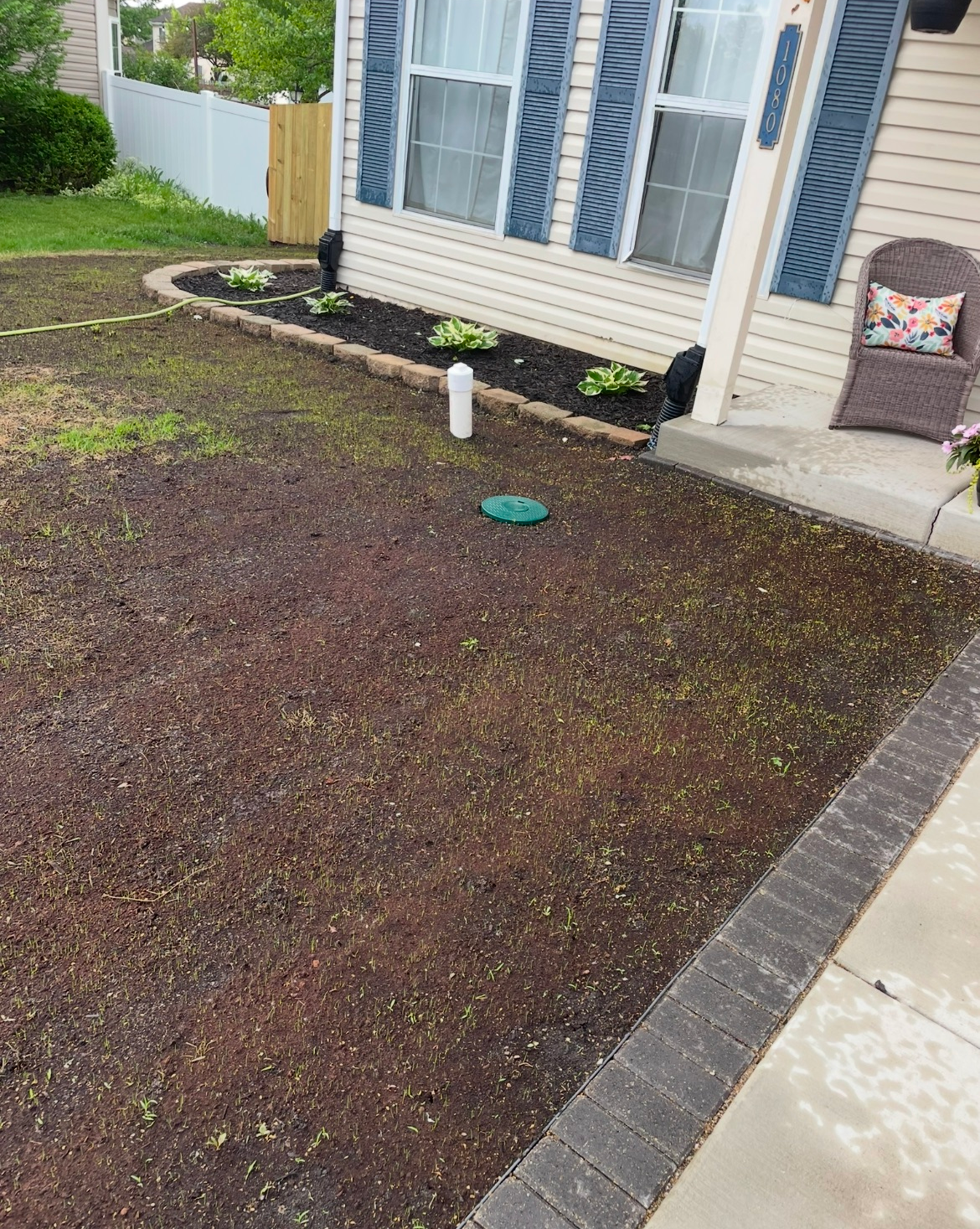 A lawn with a sprinkler in front of a house.