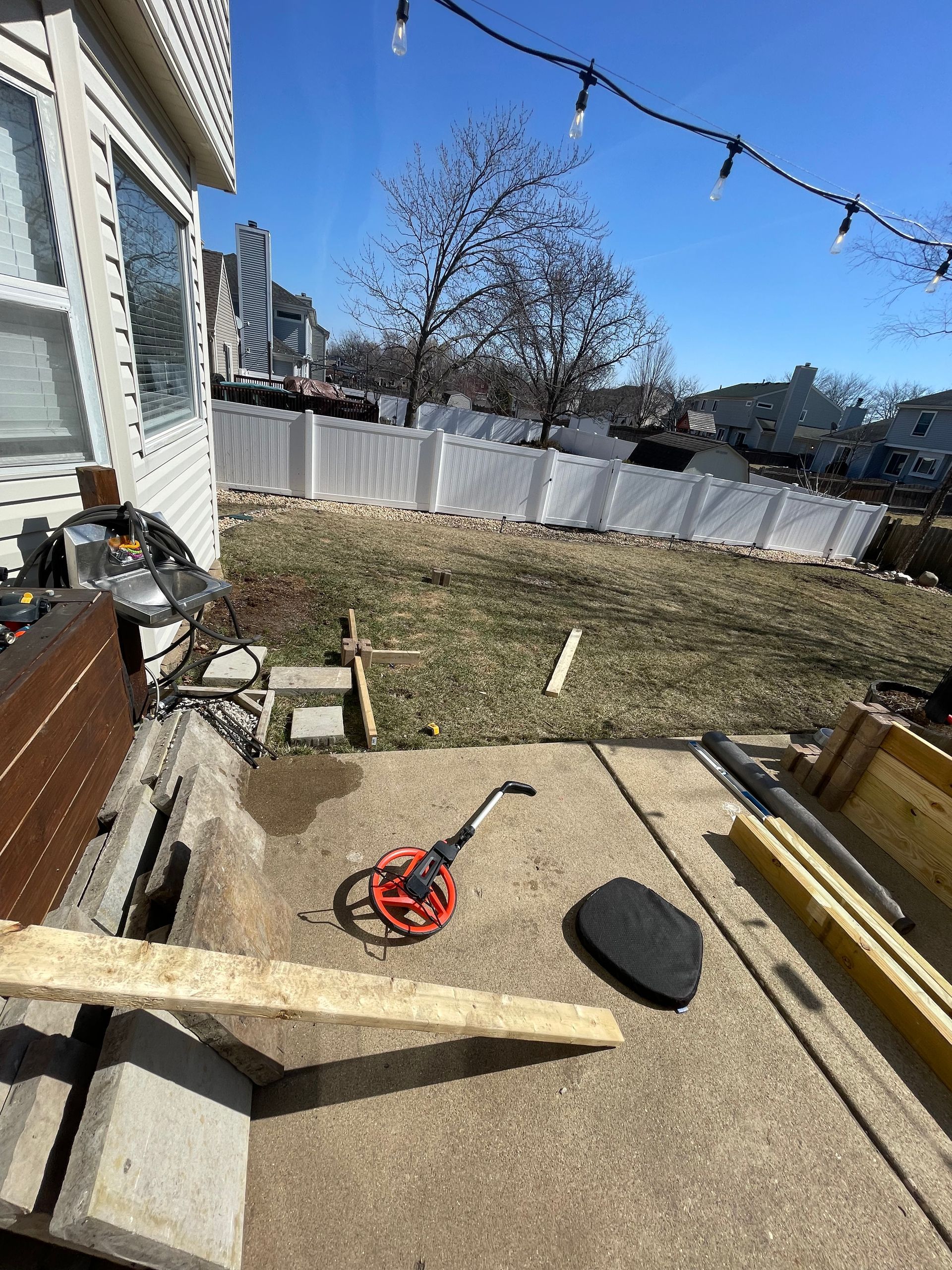 A concrete patio with a lot of tools and a fence in the background.