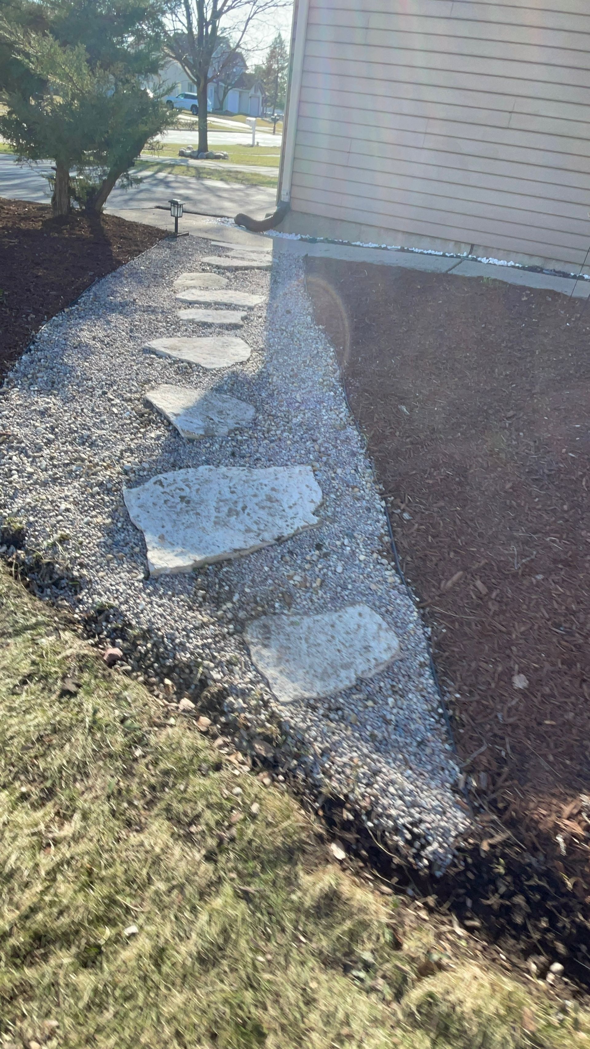 A stone walkway leading to a house with stepping stones.