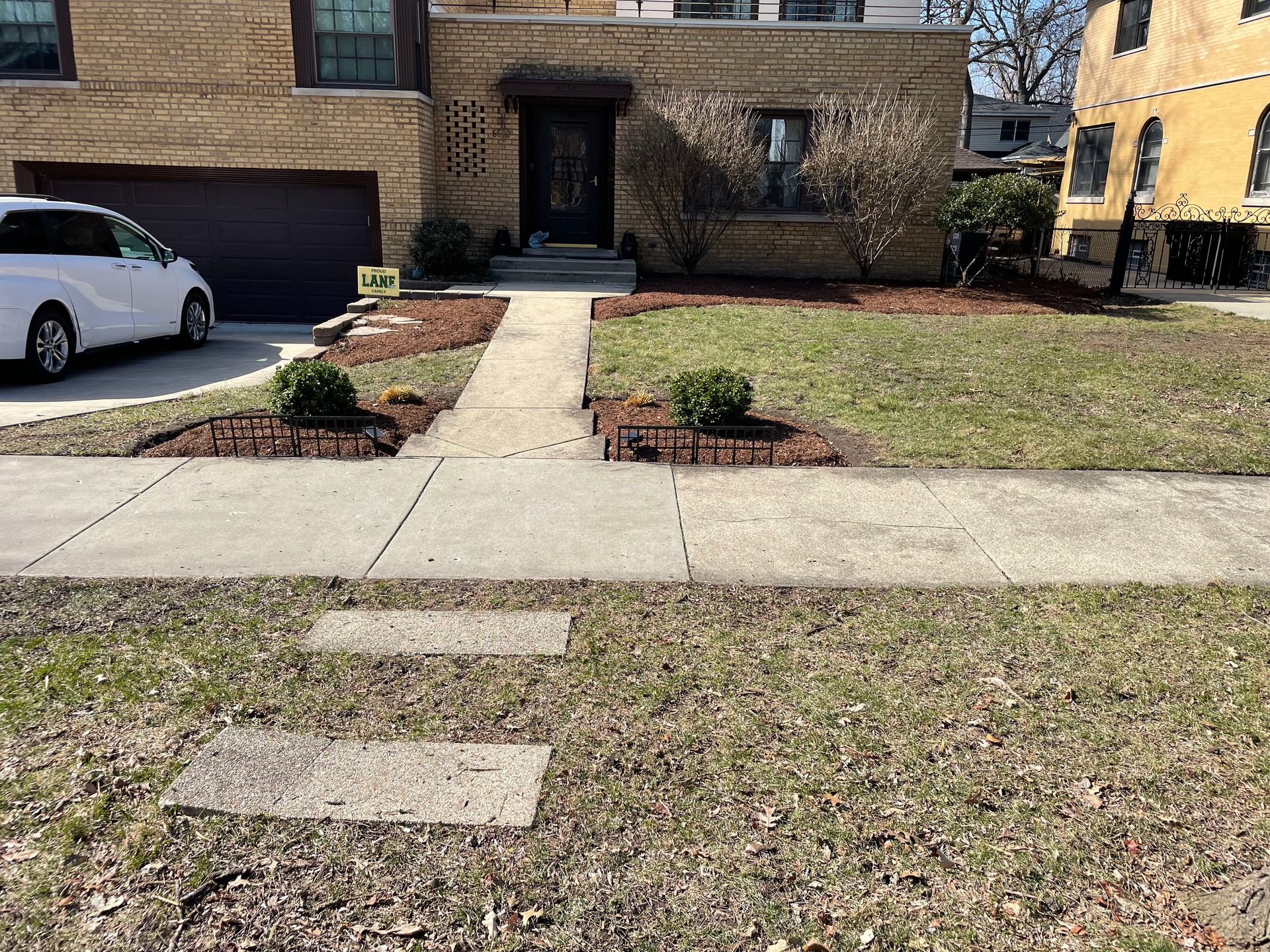 A white van is parked in front of a brick house.