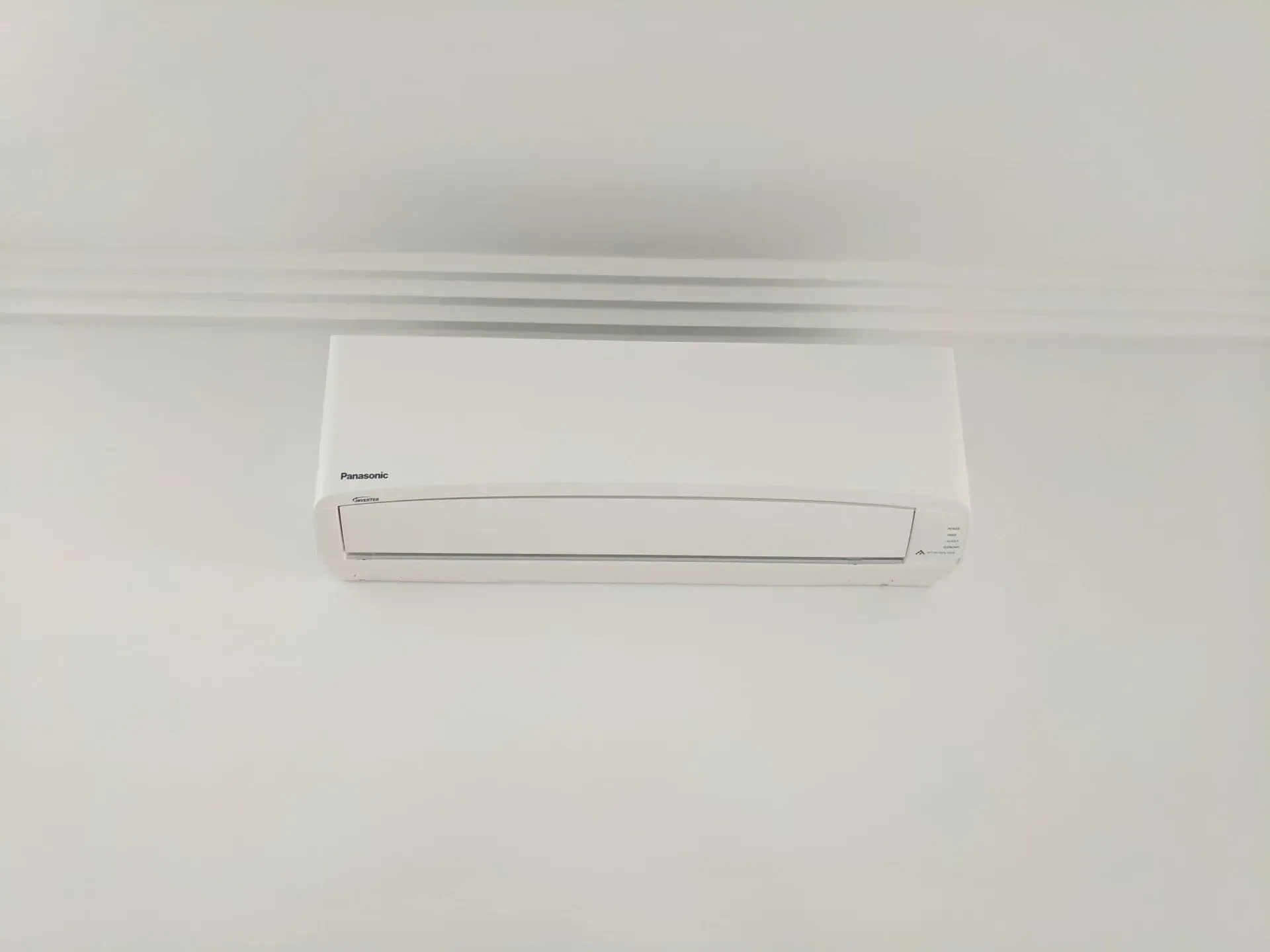 A white air conditioner is hanging on a white wall — Gleeson's Air Conditioning in Lake Cathie, NSW