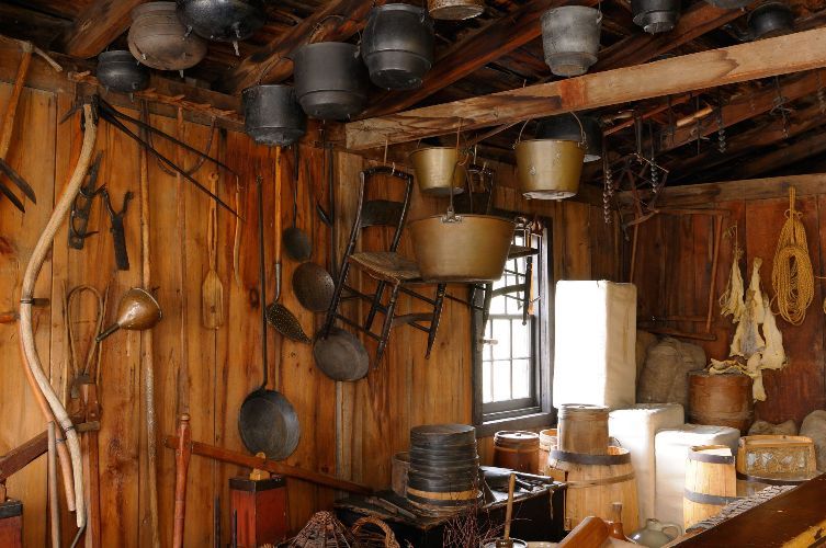 A wooden room with a lot of pots and pans hanging from the ceiling.