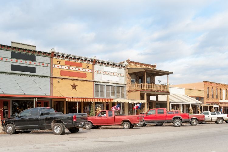 A row of trucks are parked in front of a row of buildings.