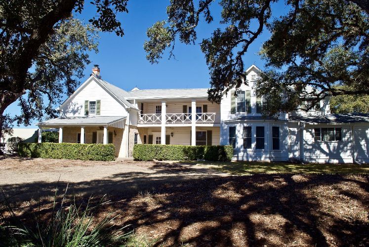 A large white house with a porch and trees in front of it