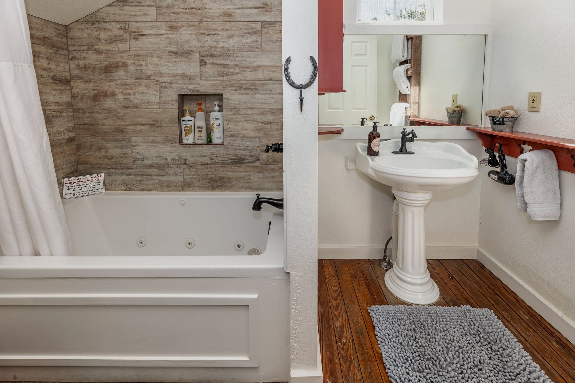 A bathroom with a tub , sink , and mirror.
