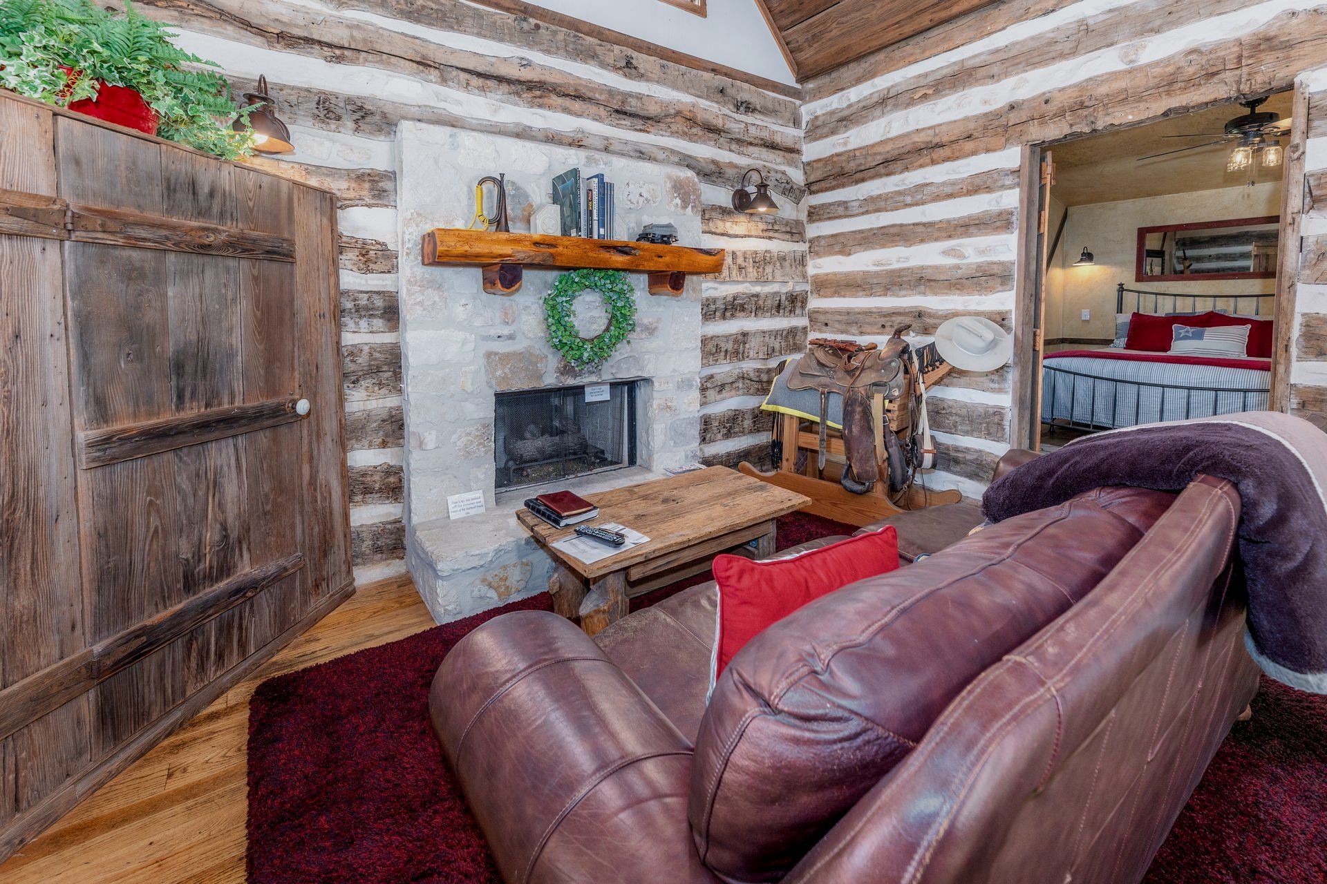 A living room in a log cabin with a couch and fireplace.