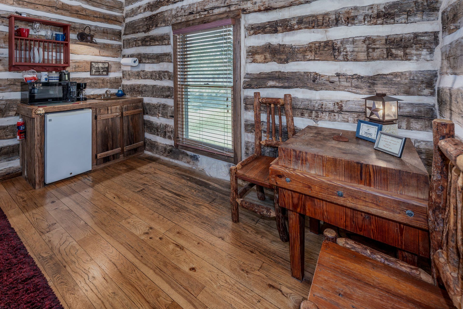 A room in a log cabin with a wooden table and chairs.