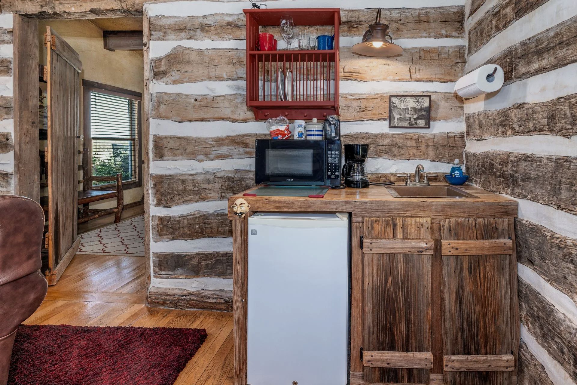 A small kitchen in a log cabin with a microwave , sink , and refrigerator.