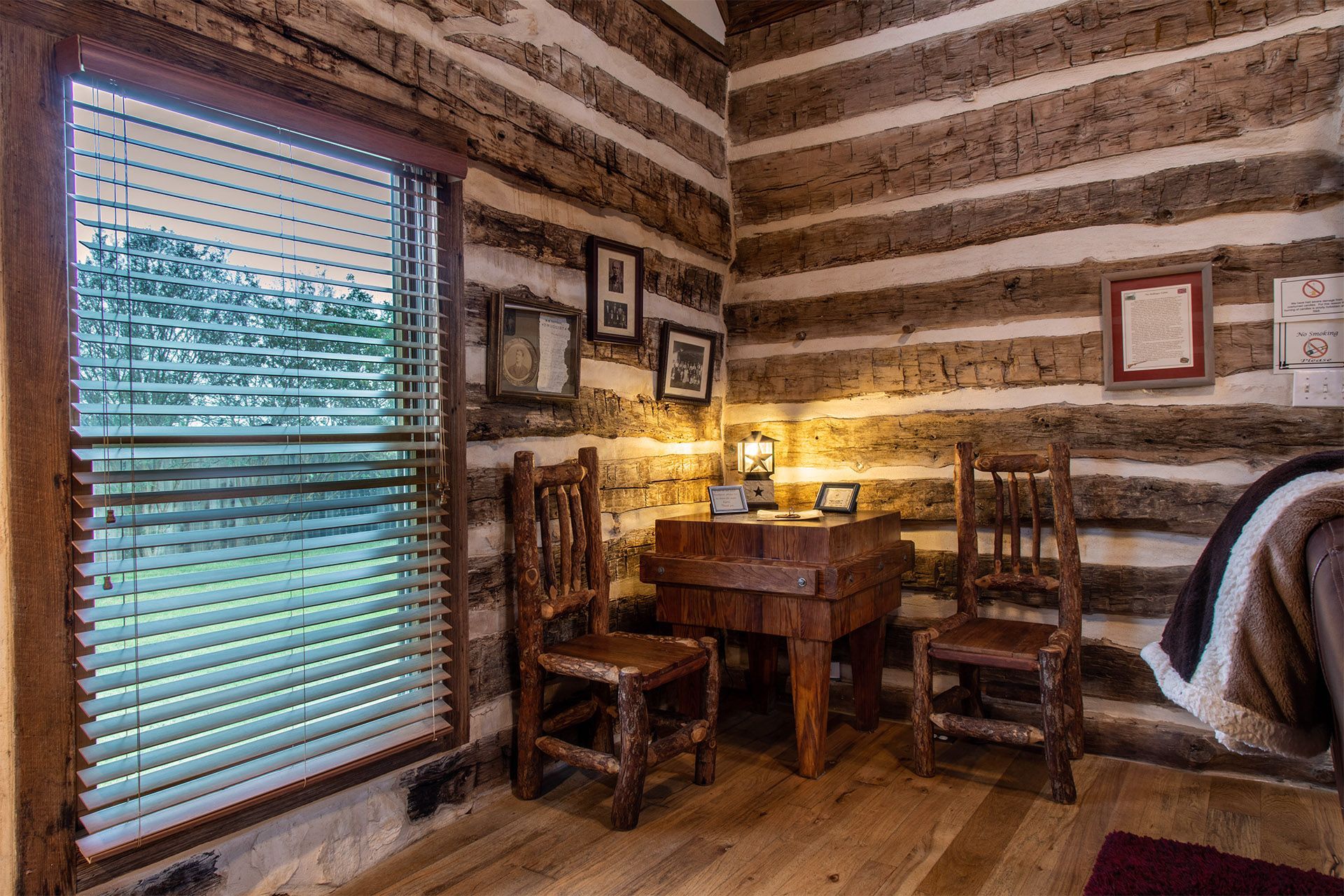 A room in a log cabin with a desk and chairs.