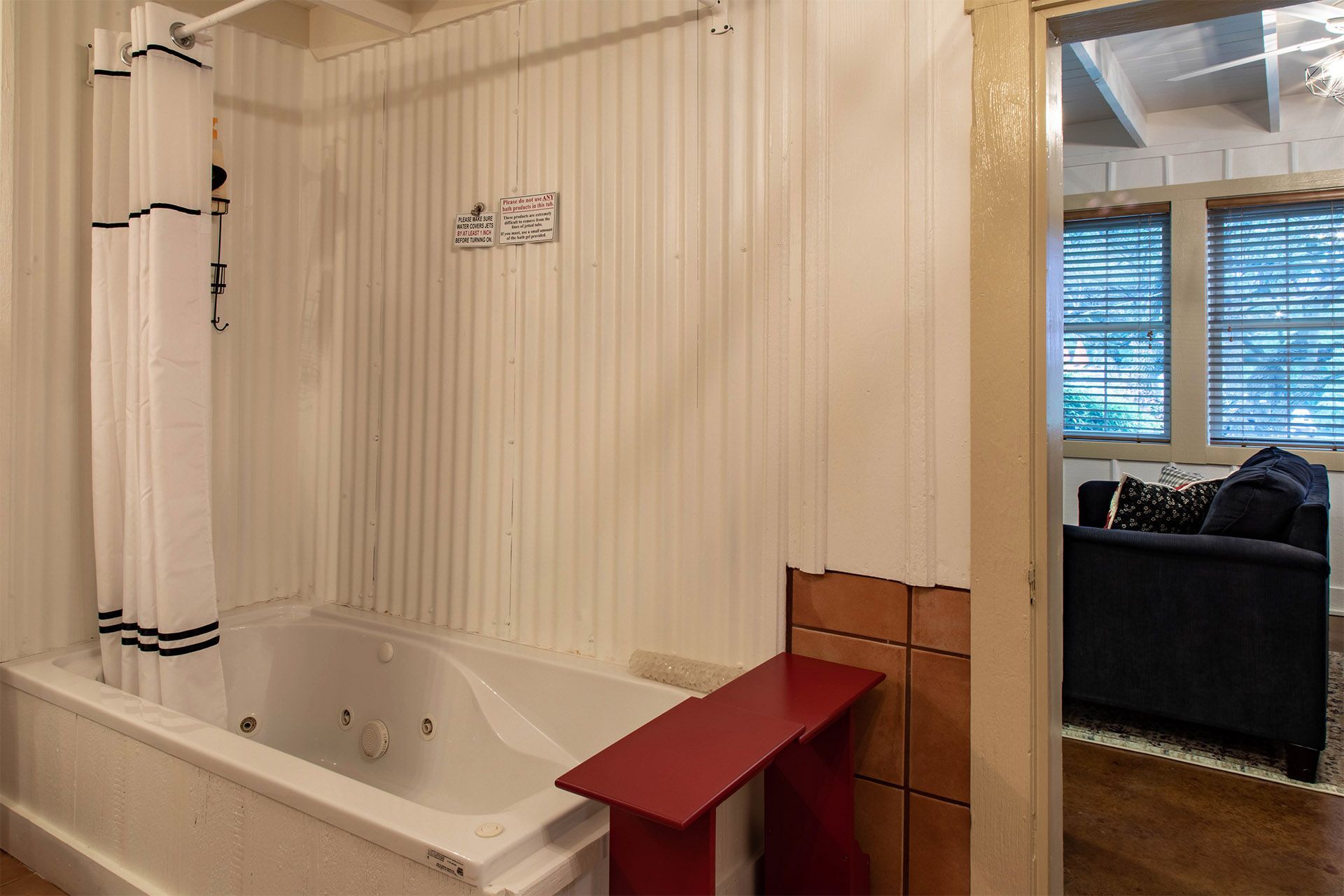 A bathroom with a jacuzzi tub and a red bench.