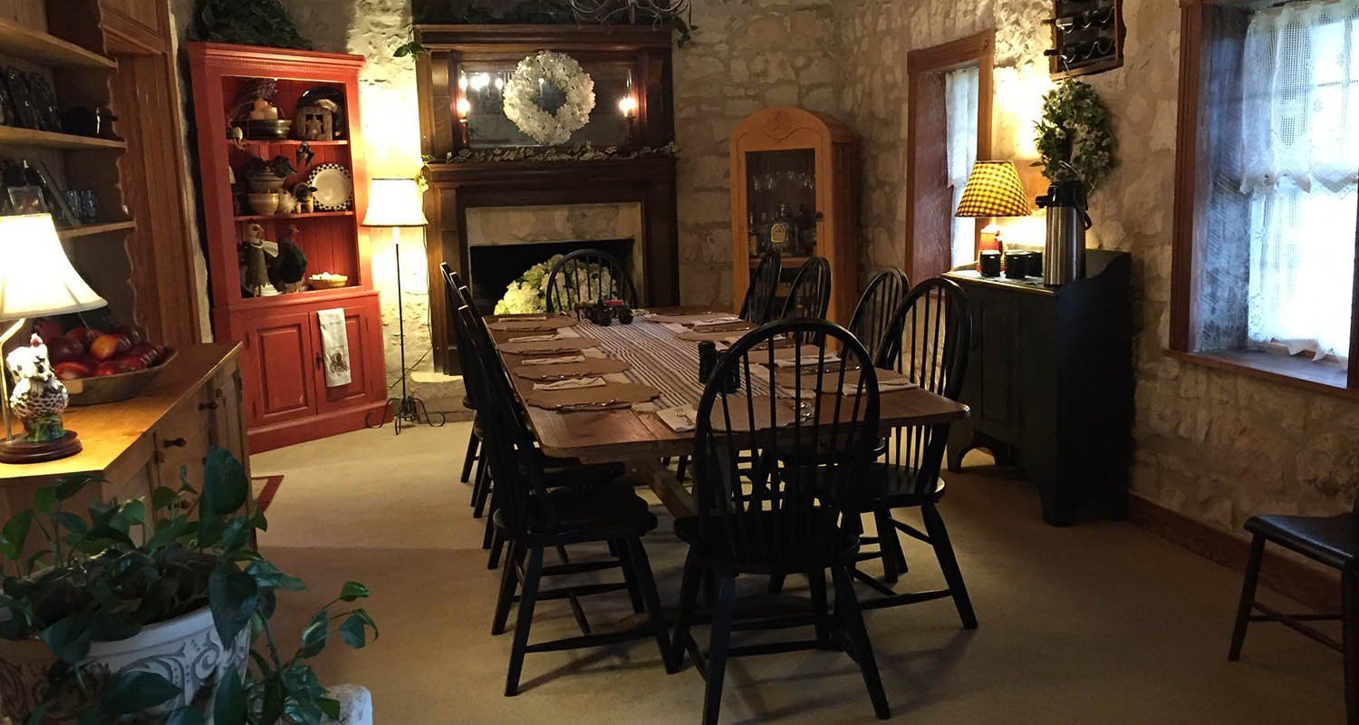 A dining room with a long table and chairs and a fireplace.