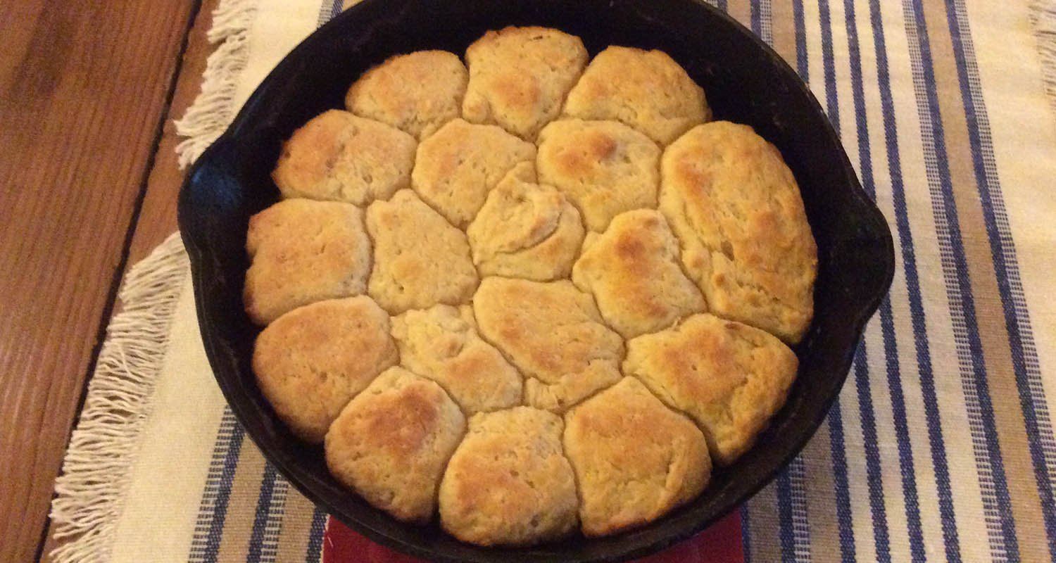 A skillet filled with biscuits is sitting on a table.