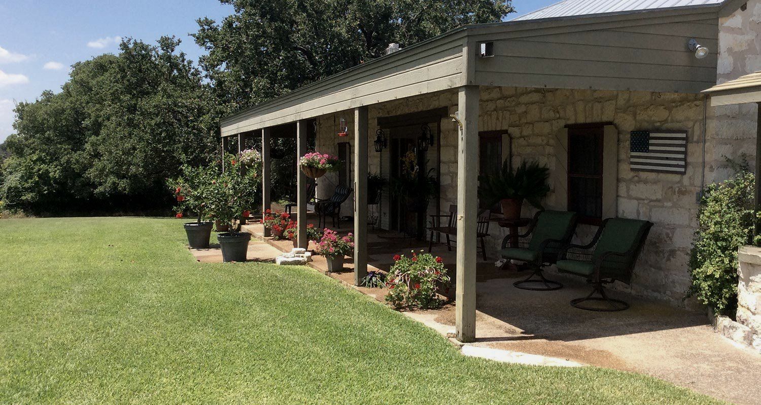 A house with a porch and chairs in front of it.