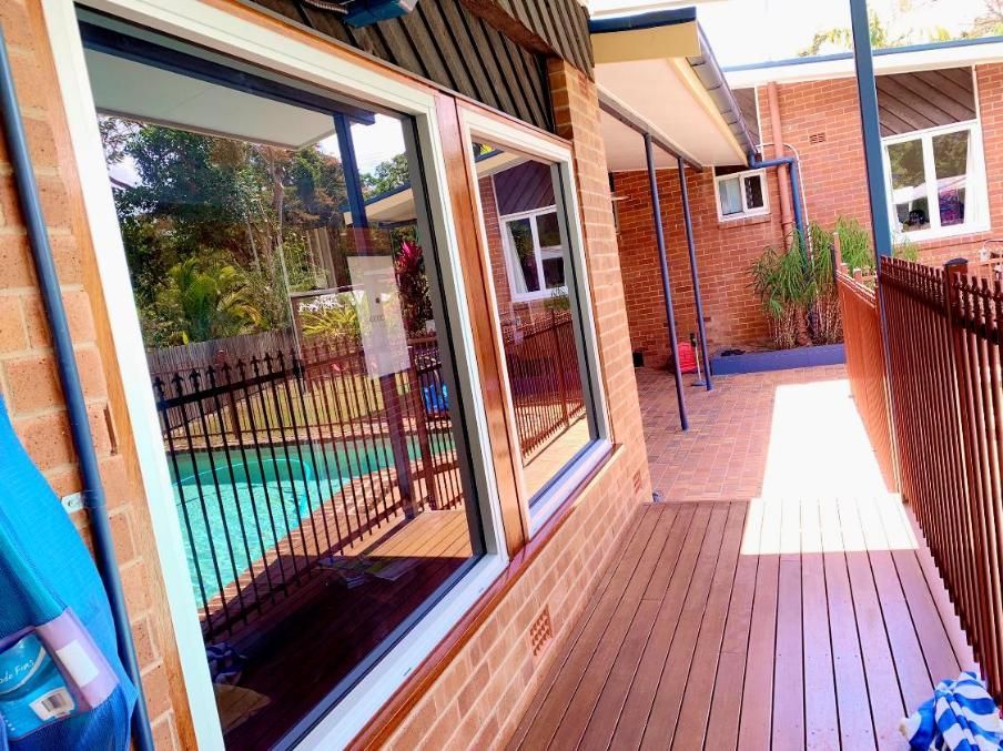 A Brick House With a Wooden Deck and a Pool in the Background — NGK Constructions In Freshwater, QLD