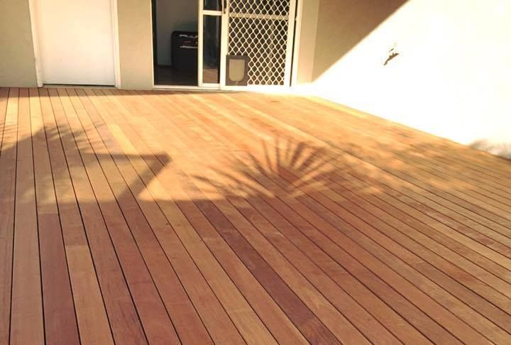 A Wooden Deck With a Shadow of a Palm Tree on It — NGK Constructions In Freshwater, QLD