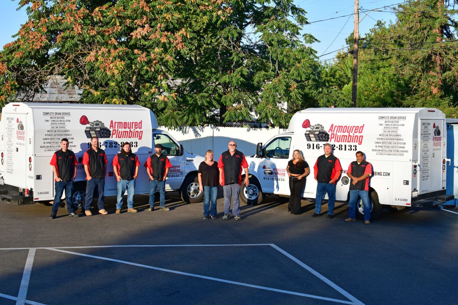 People posing with red-and-white trailers and a white van in a parking lot