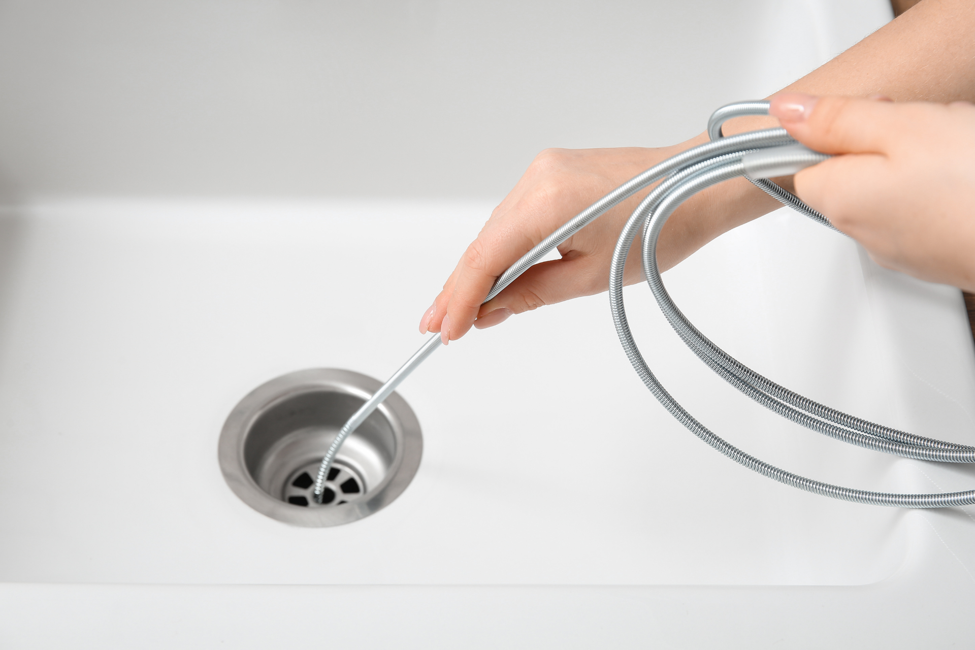 A hand holds a clear glass under a chrome kitchen faucet as water pours into the glass.