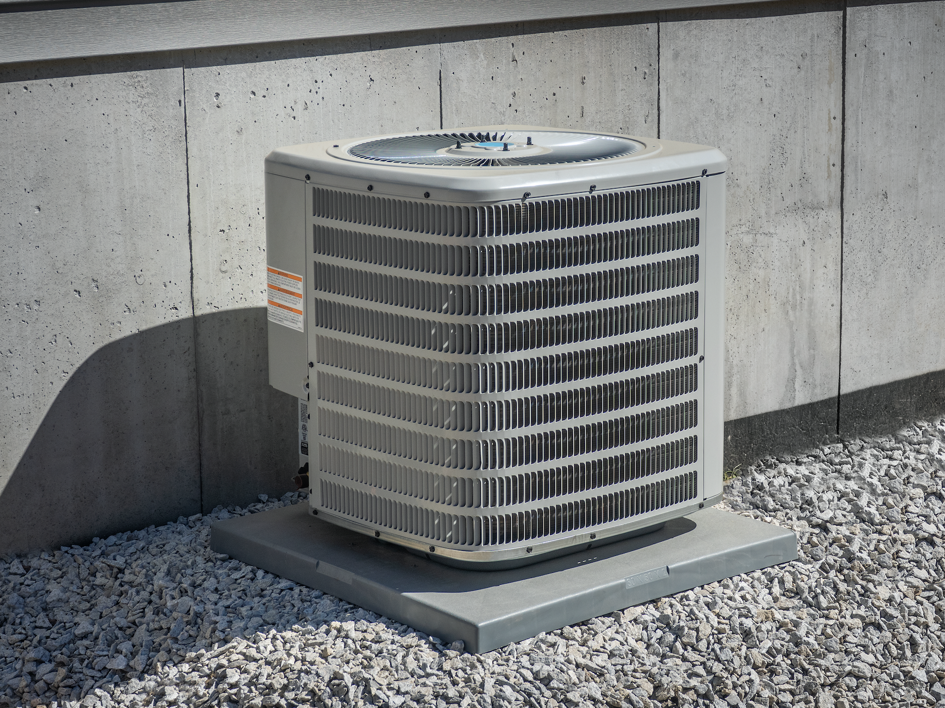 An air conditioner is sitting on top of a pile of gravel.
