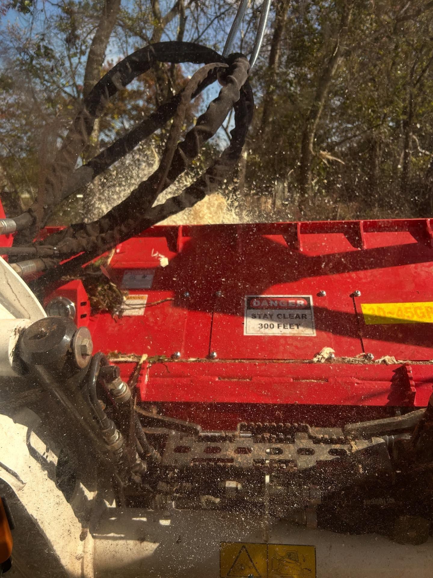 A wood chipper in action, red body, spraying wood chips.
