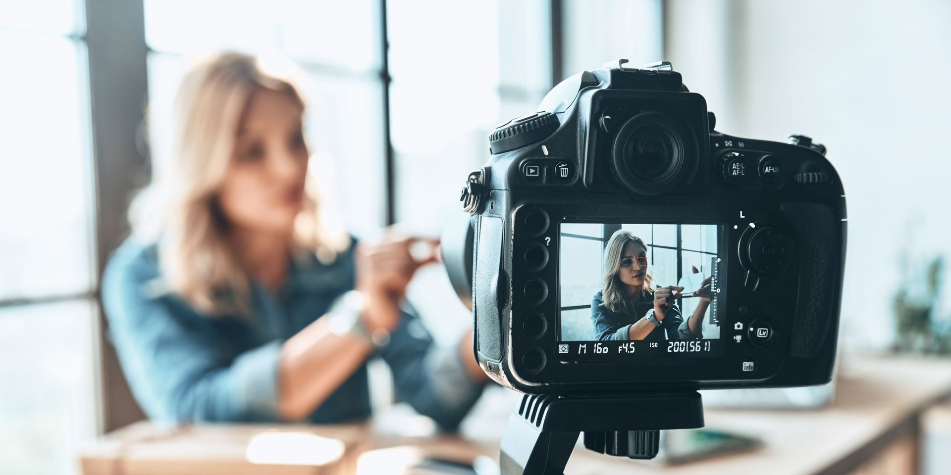 Woman explaining a concept on video being shown through the lens of a high quality camera