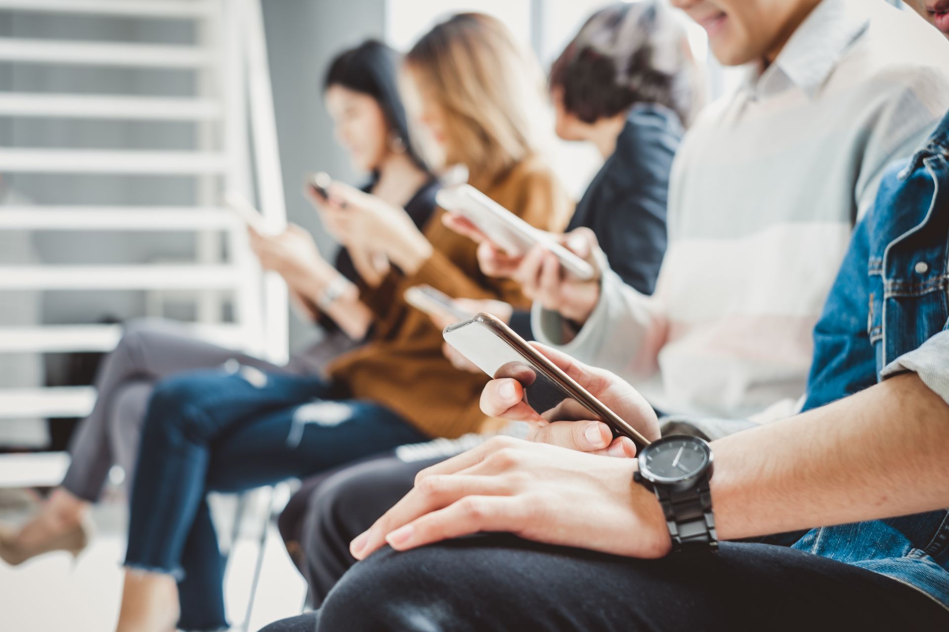 Multiple people sitting in waiting room on mobile phones