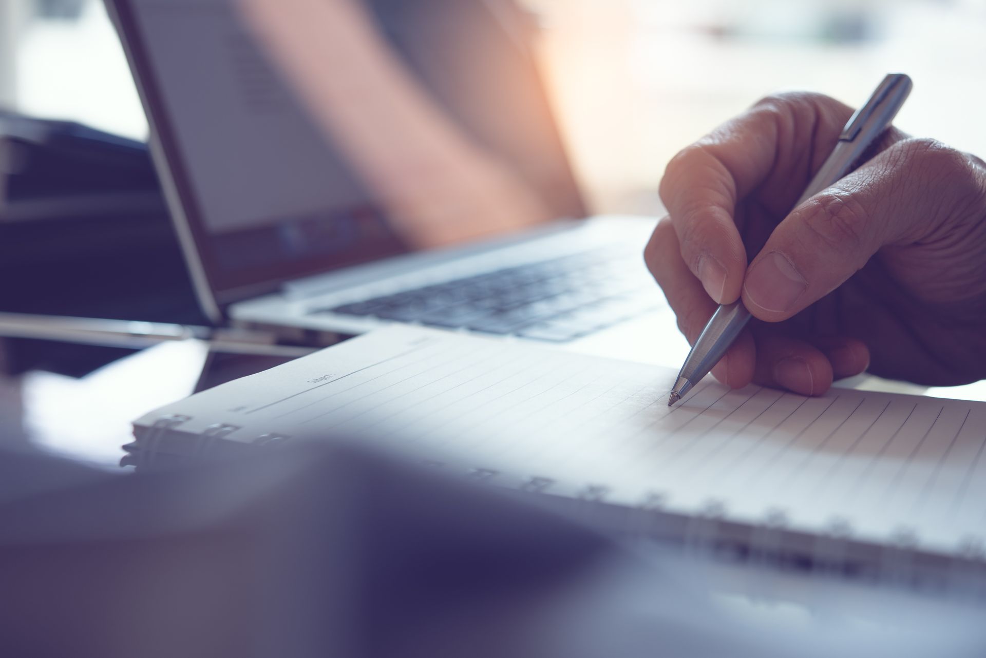 Person with notebook and computer making notes