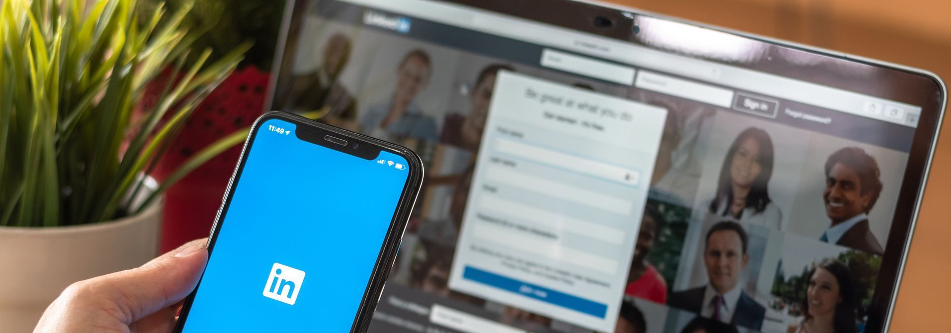 person on LinkedIn on phone in front of laptop