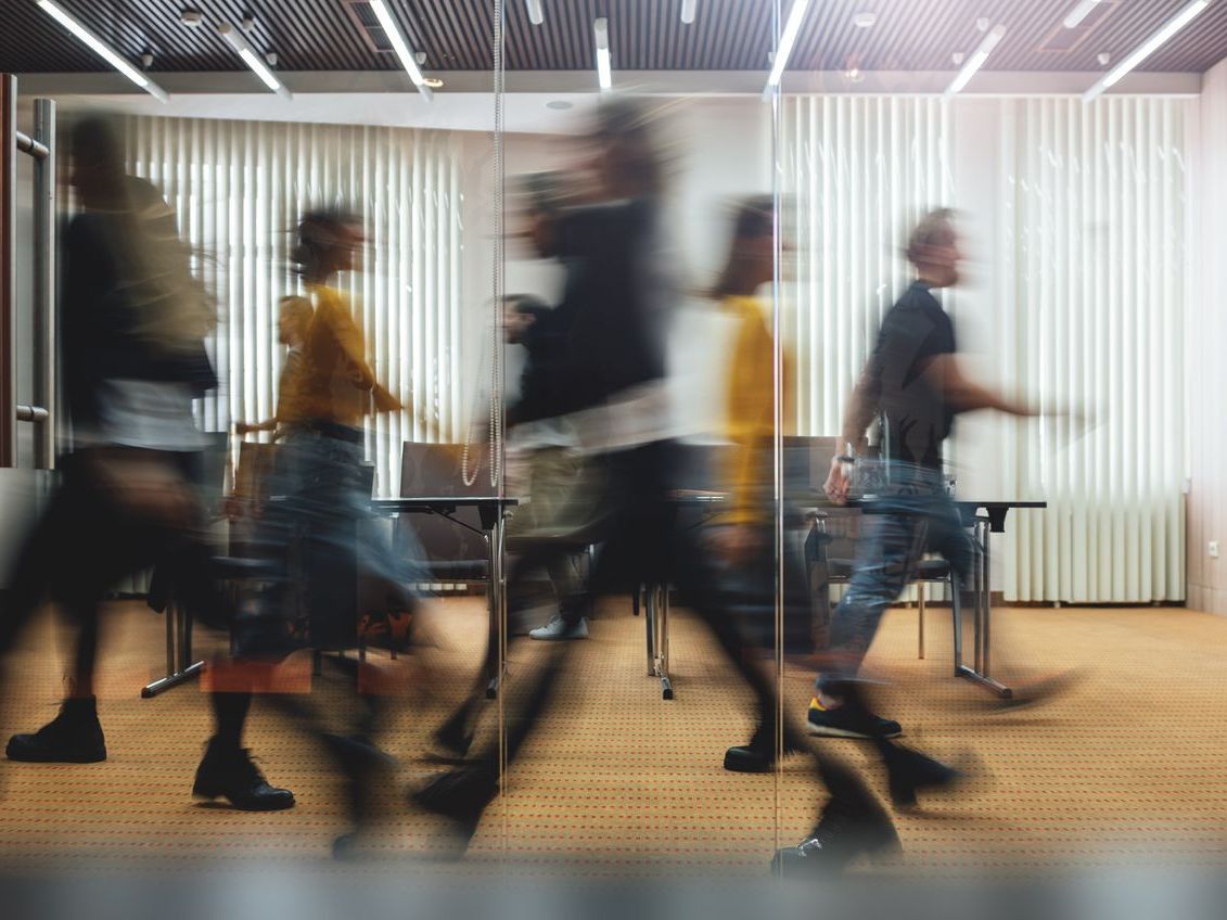 A blurry picture of a group of people walking in a room.