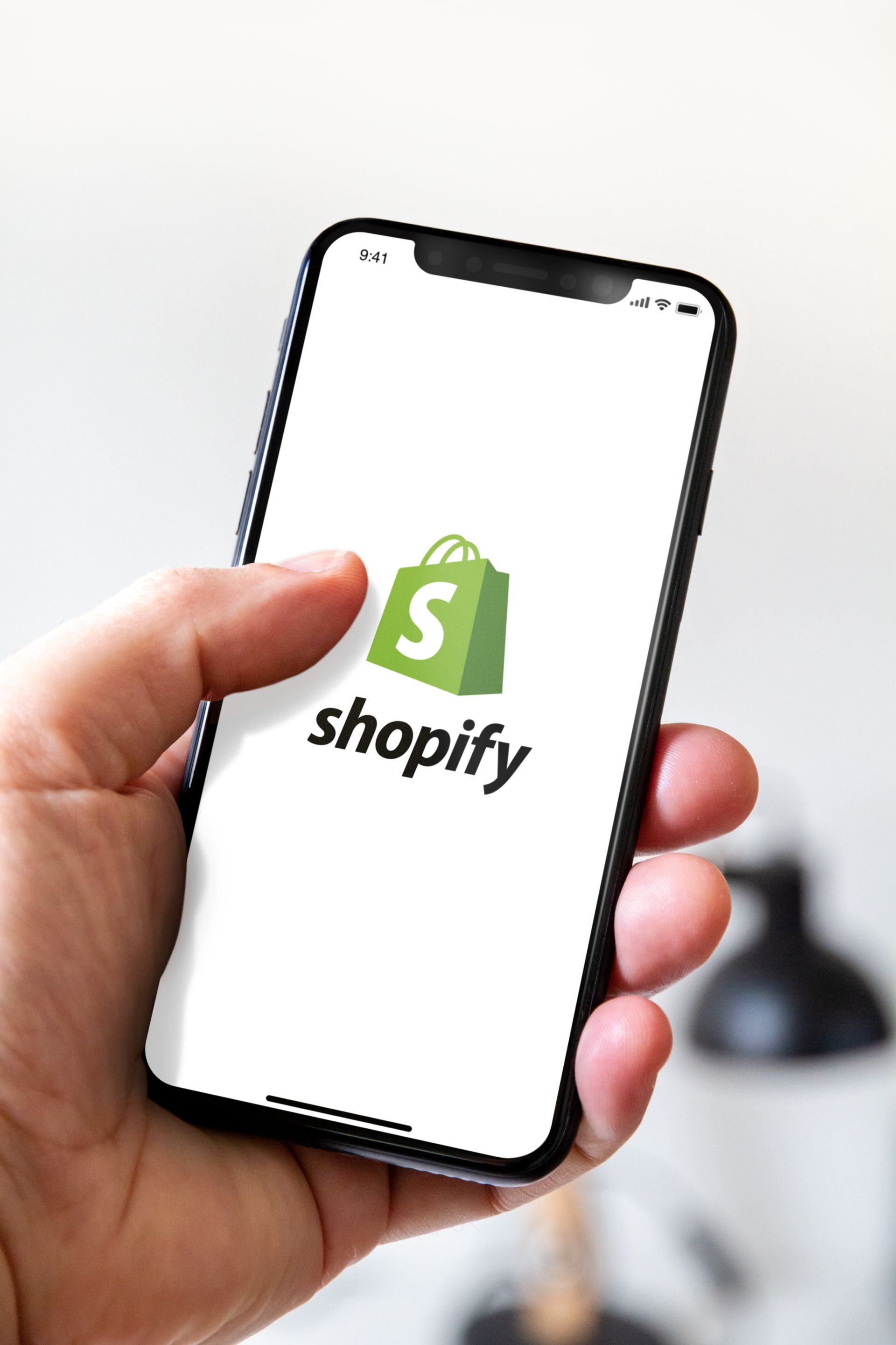 person holding phone with Shopify app