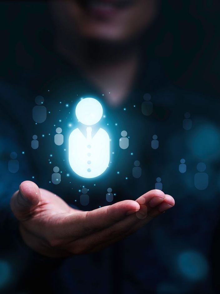 A man is holding a glowing icon of a person in his hand.